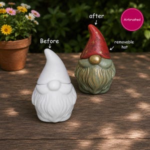 May include: Two ceramic gnome figurines. One is plain white labelled 'Before'. The other is labelled 'after' and 'removable hat', featuring a red hat with gold star accents, a gold nose, and a textured green beard. A pink circle says 'Airbrushed'.