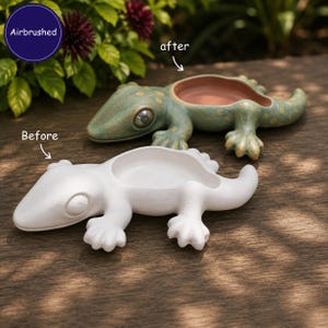 May include: Two lizard-shaped dishes, one plain white labeled 'Before' and one airbrushed green with yellow spots labeled 'after'. The green lizard has a dark interior and a realistic eye. Both feature a central bowl-like depression.