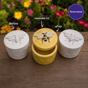 May include: Three round containers with removable lids featuring embossed bee and honeycomb patterns. Two containers are plain white, while the centre one is yellow with a painted bee. Text labels include Before, removable lid, after, and Airbrushed.