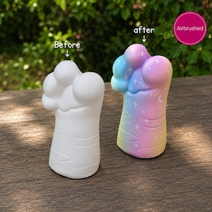 May include: Two paw-shaped figurines, one plain white labelled 'Before' and one airbrushed with a pastel rainbow gradient, star and moon details, and the label 'after'. The airbrushed figurine features blue, pink, and yellow colours.
