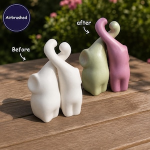 May include: Two pairs of elephant figurines. One pair is solid white, labeled 'Before'. The other pair is airbrushed in pastel green and pink, labeled 'after'. The elephants are positioned with their trunks intertwined, creating a heart-like shape.