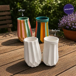May include: Four geometric vases with a faceted design. Two vases are plain white, labelled as 'Before'. Two vases are airbrushed with vertical stripes in pink, green, yellow, and teal, labelled as 'after'. The vases are arranged on a wooden surface.