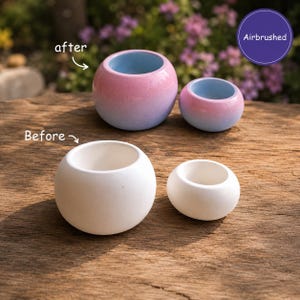 May include: Two pairs of round ceramic planters are displayed. The top pair features an airbrushed pink and blue gradient finish with light blue interiors. The bottom pair consists of two plain white, unpainted ceramic planters of similar shapes.