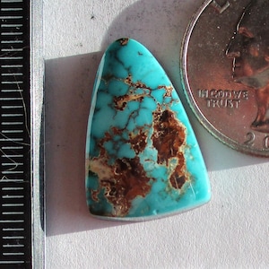 May include: A triangular Royston turquoise gemstone with brown matrix, positioned next to a 2021 US quarter and a ruler showing measurements in inches. The text reads Natural Royston DIN-131-R 13.6ct. The stone displays a vibrant blue-green color.