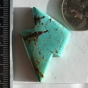May include: A turquoise lightning bolt-shaped stone with brown veining, next to a US quarter. The stone is labeled "Stabilized Kingman Lightning Bolts LN-16-K 45.0ct."