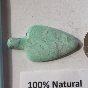 May include: A light green Apache Variscite gemstone, shaped like a teardrop, with a natural, rough texture. The gemstone is 31.40 carats and is labeled "100% Natural Apache Variscite FQ-007-AV 31.40ct."