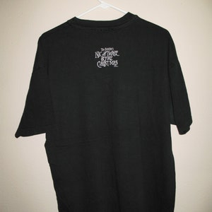 May include: Black t-shirt with "Tim Burton's Nightmare Before Christmas" printed on the back in white.