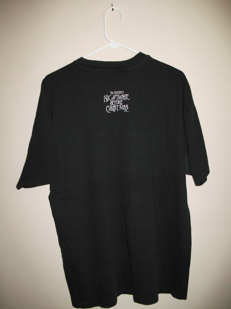 May include: Black t-shirt with "Tim Burton's Nightmare Before Christmas" printed on the back in white.