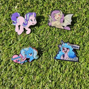 May include: Four enamel pins of cartoon ponies. One pink pony with purple hair, one with bat wings, and two with blue hair. One pin says "Sounds Gay I'm in" and another says "Everything is better with Glitter!"