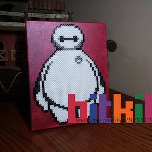 May include: A red canvas with a white and black pixel art image of Baymax from the movie Big Hero 6. The image is on a red canvas with the text "www.etsy.com/shop/BitKitUSA" at the bottom.