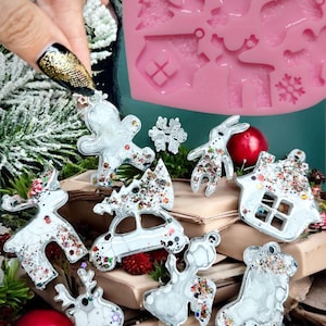 以下が含まれることがあります： キラキラと輝く銀色のアクセントが施された透明なレジン製のクリスマスオーナメント10個セット。オーナメントは、クリスマスツリー、トナカイ、ジンジャーブレッドマン、家、靴下、車の形をしています。オーナメントは、ピンクのシリコンモールドを背景に、本の積み重ねの上に飾られています。