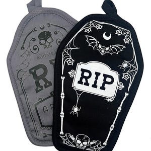 Peut inclure: Deux maniques en forme de cercueil. L'une est grise avec un crâne et le mot "RIP". L'autre est noire avec un motif de pierre tombale "RIP" blanc, des chauves-souris, des araignées et un crâne. Les deux ont une boucle pour suspendre.