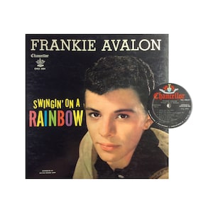 Könnte beinhalten: Frankie Avalon Albumcover mit einem Schwarzweißfoto von Frankie Avalon und dem Albumtitel "Swingin' on a Rainbow" in Regenbogenfarben. Das Album ist auf dem Label Chancellor.