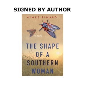 Può includere: Copertina di un libro con il titolo "THE SHAPE OF A SOUTHERN WOMAN" in testo blu e bianco. La copertina presenta un'illustrazione ad acquerello di due cicale e il testo "SIGNED BY AUTHOR". Il nome dell'autore, Aimee Pinard, è in alto.