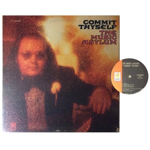 Może przedstawiać: Okładka albumu "Commit Thyself" zespołu The Music Asylum. Okładka przedstawia rozmyty obraz osoby w ciemnym garniturze na ciepłym, pomarańczowym tle. Tytuł albumu i nazwisko artysty są wydrukowane pogrubioną, stylizowaną czcionką. Widoczna jest płyta winylowa.