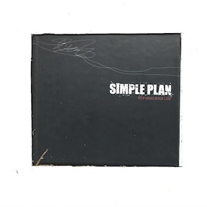 May include: A black DVD case with a white inscription that reads "SIMPLE PLAN MTV HARD ROCK LIVE".