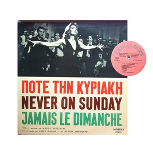 May include: A vintage record album cover featuring a black and white photo of a woman in a black dress with a group of people behind her. The album title is "Pote Thln Kyriaki Never On Sunday Jamais Le Dimanche" in red, white, and green text. The album is by Manos Hadjidakis and Jules Dassin with Melina Mercouri.