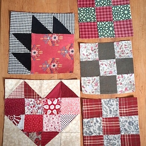 May include: Five square fabric quilt blocks featuring various patterns and colours. One block displays a heart shape in red and white, another a black and white star, and three others feature grid-based designs with floral, plaid, and geometric prints.