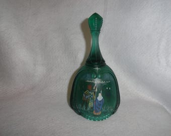 Puede incluir: Campana decorativa de vidrio verde con cuello largo y parte superior puntiaguda. La campana presenta una escena pintada con figuras con túnicas y una estrella. La campana es de vidrio verde.