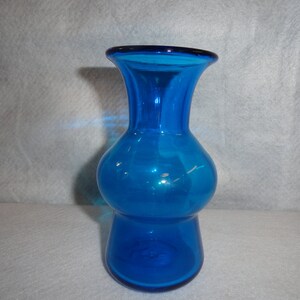 May include: A vibrant blue glass vase with a bulbous body and flared top. The vase has a glossy finish and a dark blue rim. This decorative vase is suitable for displaying flowers or as a standalone accent piece.
