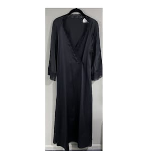 May include: A long, black nightgown with a V-neckline and long sleeves. The neckline and sleeve cuffs are trimmed with delicate lace. The nightgown is made of a smooth, silky fabric and hangs on a black hanger.