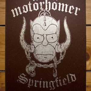 May include: A brown poster with a silver metallic print of a cartoon character with horns and a chain. The character has a serious expression and is wearing a helmet. The text "Motörhead" and "Springfield" are printed in silver metallic lettering.