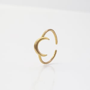 Könnte beinhalten: Ein goldener Halbmondring. Der Ring besteht aus einem einzigen Stück Metall und hat ein schlichtes, elegantes Design.