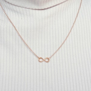 Peut inclure: Un collier délicat en chaîne dorée avec un pendentif en forme d'infini.