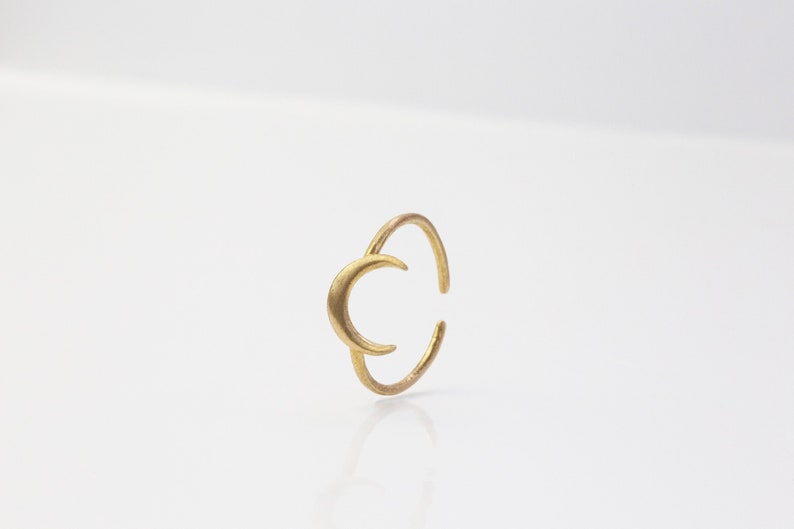 Puede incluir: Un anillo de oro en forma de media luna. El anillo est&aacute; hecho de una sola pieza de metal y tiene un dise&ntilde;o simple y elegante.