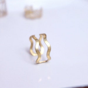 Peut inclure: Une bague en or avec un motif ondulé. La bague est composée de deux pièces de métal qui sont assemblées.