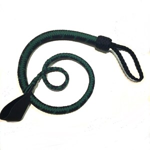 May include: A braided whip with a black handle and a green and black braided body. The whip is coiled and has a loop at the end. The handle is made of a smooth, black material.