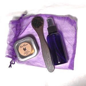 Könnte beinhalten: Eine violette Netz-Tasche mit einer Holzbürste, einer kleinen Dose mit dem Etikett "Bet House Glycerin Toothblackening Soap" und einer durchsichtigen Flasche mit einem violetten Sprühkopf.