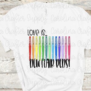 May include: White t-shirt with the text "Love is... New Flair Pens!" printed on it. The text is in black and there are 12 colorful pens arranged vertically next to the text.