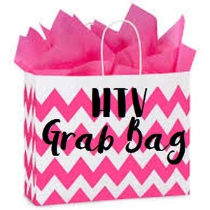 Op de afbeelding: Een witte cadeauzak met roze zigzagpatroon met de tekst "HTV Grab Bag" in zwart.