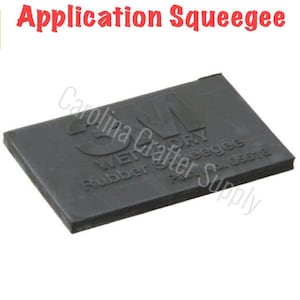Puede incluir: Una escobilla de goma negra con el texto "3M Wetordry Rubber Squeegee Part No. 05512" en relieve.