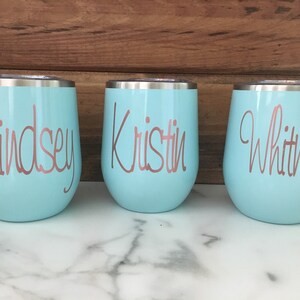 May include: Three light blue stainless steel tumblers with rose gold lettering. The tumblers are labeled "Lindsey", "Kristin", and "Whitney".