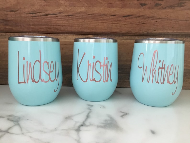 May include: Three light blue stainless steel tumblers with rose gold lettering. The tumblers are labeled "Lindsey", "Kristin", and "Whitney".