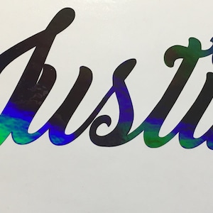 May include: A black vinyl decal with the name "Justin" written in a cursive font. The decal has a holographic finish that shimmers with rainbow colors.