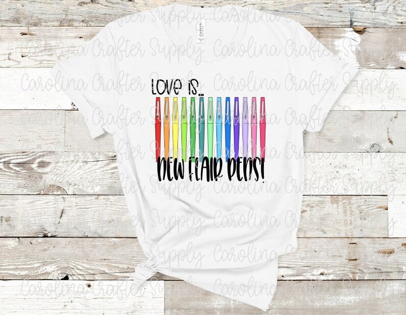 May include: White t-shirt with the text "Love is... New Flair Pens!" printed on it. The text is in black and there are 12 colorful pens arranged vertically next to the text.