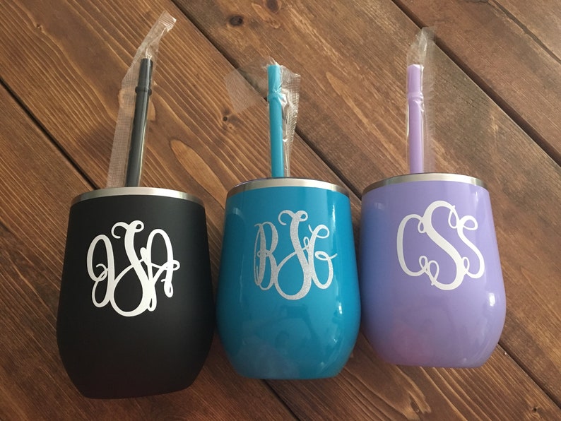 May include: Three stainless steel tumblers with personalized monograms and matching straws. The tumblers are black, teal blue, and lavender.