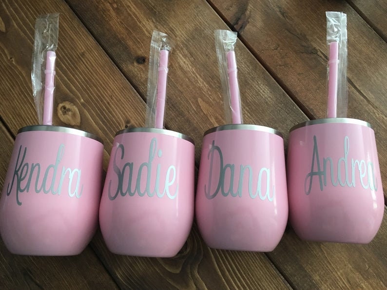 May include: Four pink stainless steel tumblers with silver straws and personalized names: Kendra, Sadie, Dana, and Andrea.
