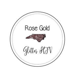 May include: A white circle with a black outline and a dotted line around the edge. Inside the circle is a rose gold glitter outline of the state of North Carolina. The text "Rose Gold Glitter HTV" is written below the state outline.