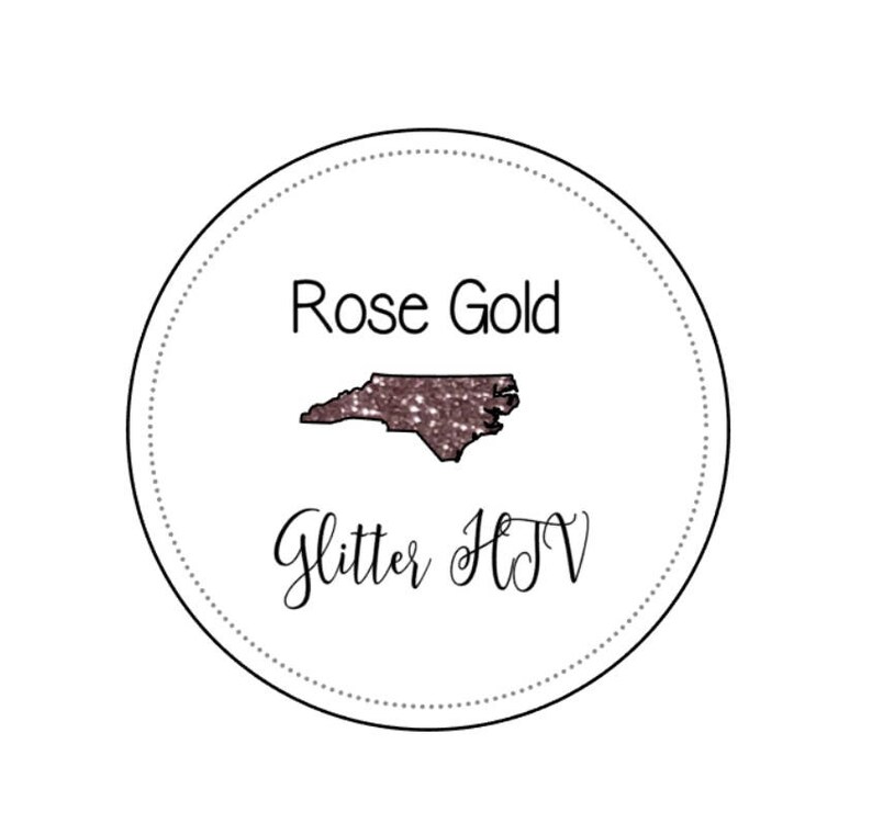 May include: A white circle with a black outline and a dotted line around the edge. Inside the circle is a rose gold glitter outline of the state of North Carolina. The text "Rose Gold Glitter HTV" is written below the state outline.