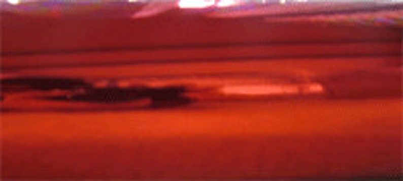 May include: A close-up of a red metallic surface with a slight sheen. The surface is smooth and reflective.