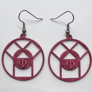 May include: A pair of pink earrings with a geometric design featuring a circle with a triangle inside and the Greek letter Phi in the center. The earrings have silver hooks.