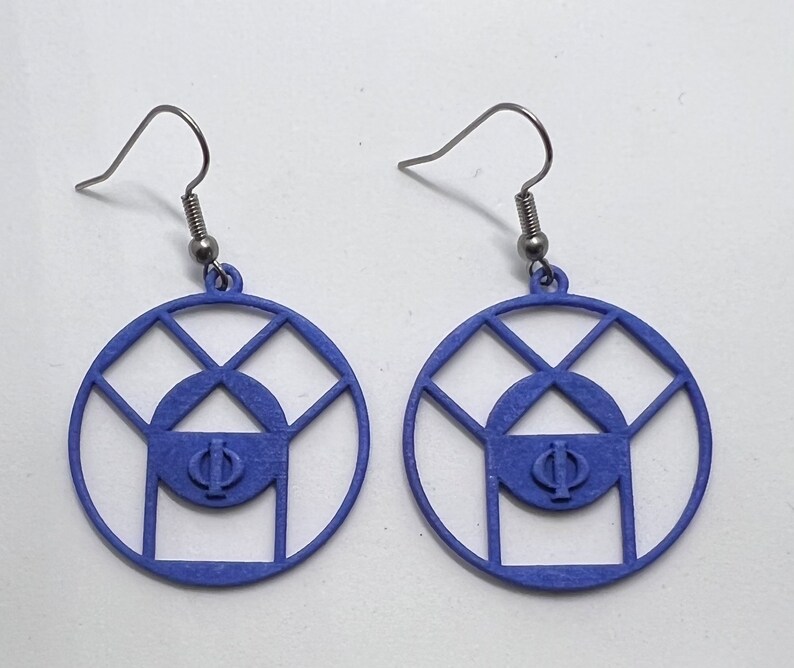 May include: A pair of blue earrings with a geometric design featuring a circle with a smaller circle inside and the Greek letter Phi in the center. The earrings are made of a lightweight material and have a silver hook.
