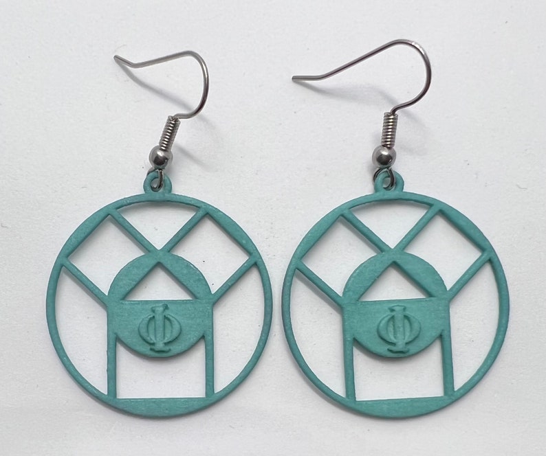 May include: A pair of teal blue earrings with a geometric design featuring a circle with a triangle inside and the Greek letter Phi. The earrings are made of metal and have silver hooks.