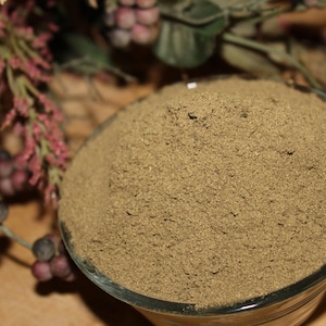 May include: A close-up of a glass bowl filled with a light brown powder. The powder is finely ground and has a uniform texture.