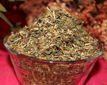 May include: A glass bowl filled with dried herbs, a blend of green and brown, with a pink background.