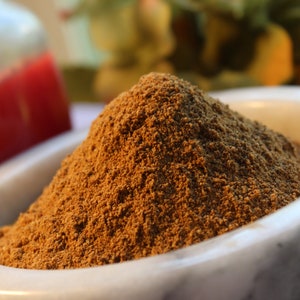 May include: A close-up of a white marble mortar and pestle filled with a mound of ground brown spice.